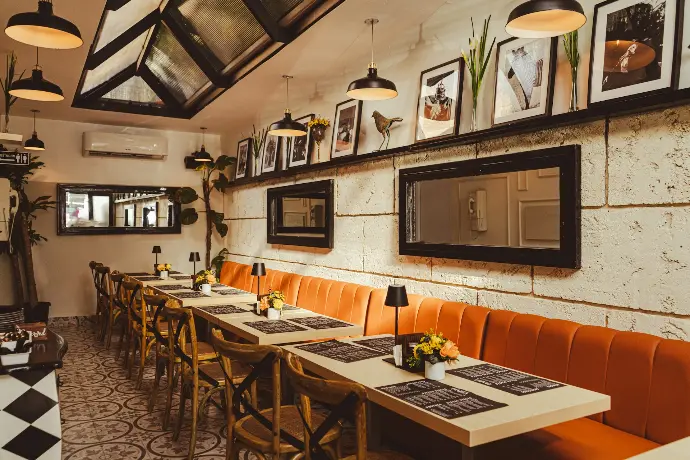 a restaurant with a long table and orange benches